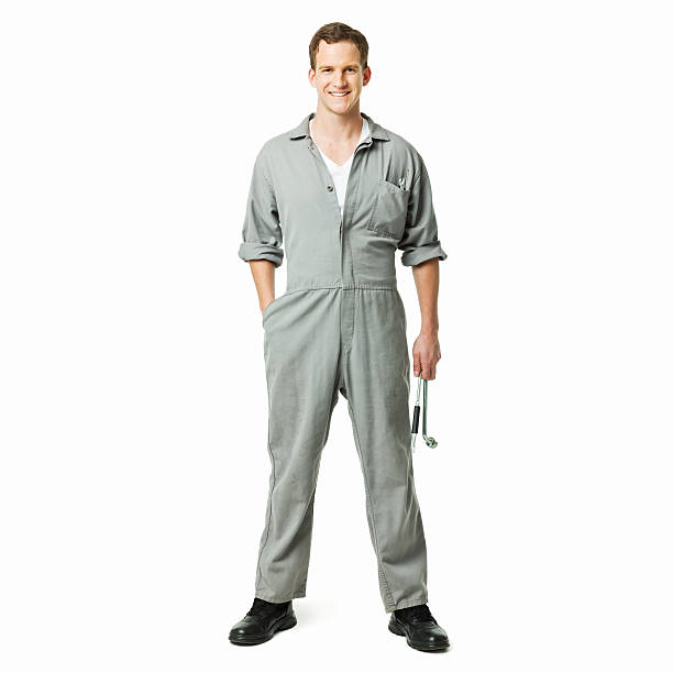 Young automotive technician standing in coveralls and holding a wrench. Square shot. Isolated on white.
