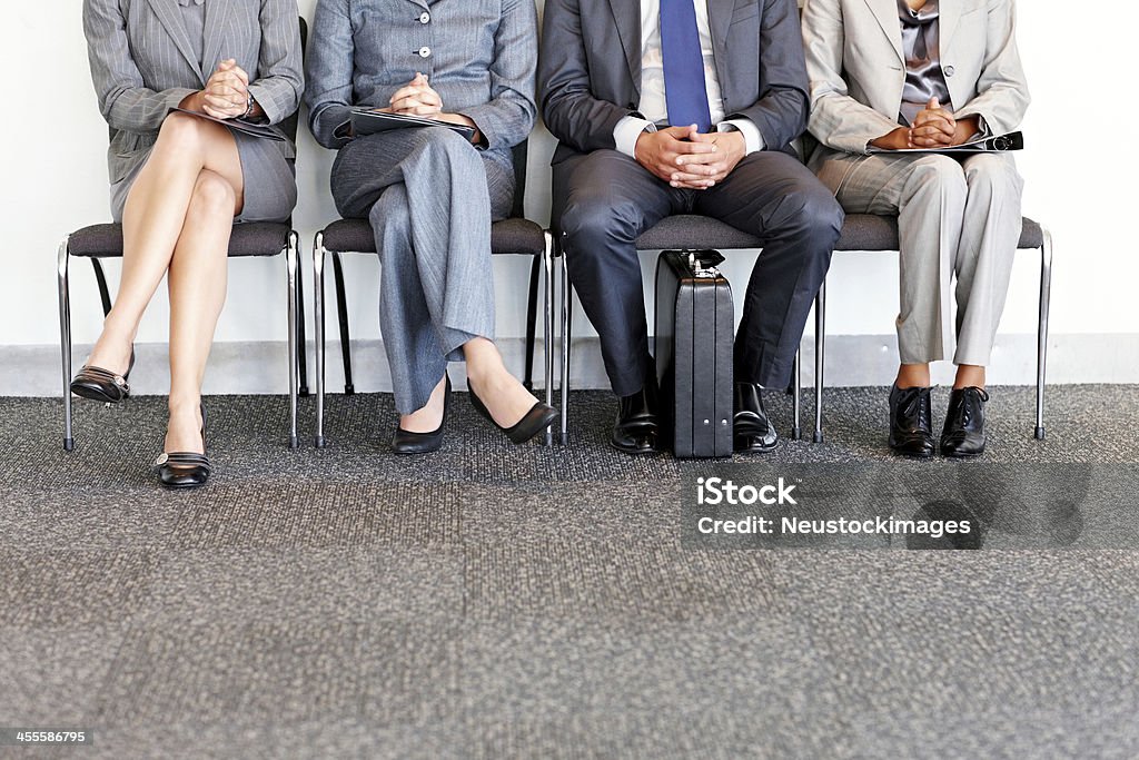 Business People Waiting in Chairs Lower body view of a row of business people waiting in chairs. Horizontal shot. Business Stock Photo