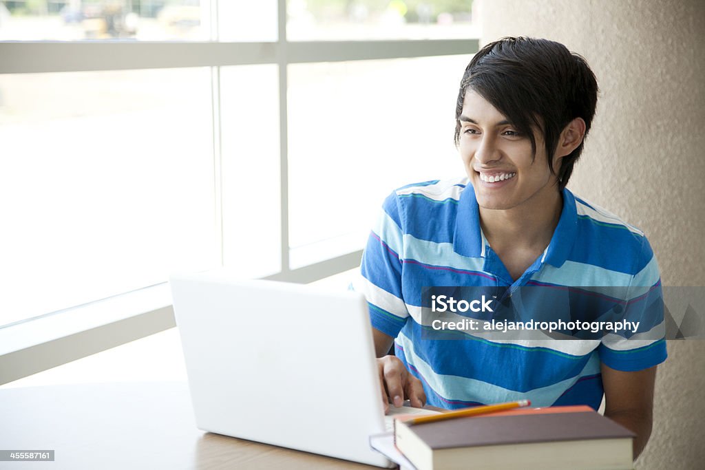 Hispanic studente sorridente su computer portatile - Foto stock royalty-free di Abbigliamento casual