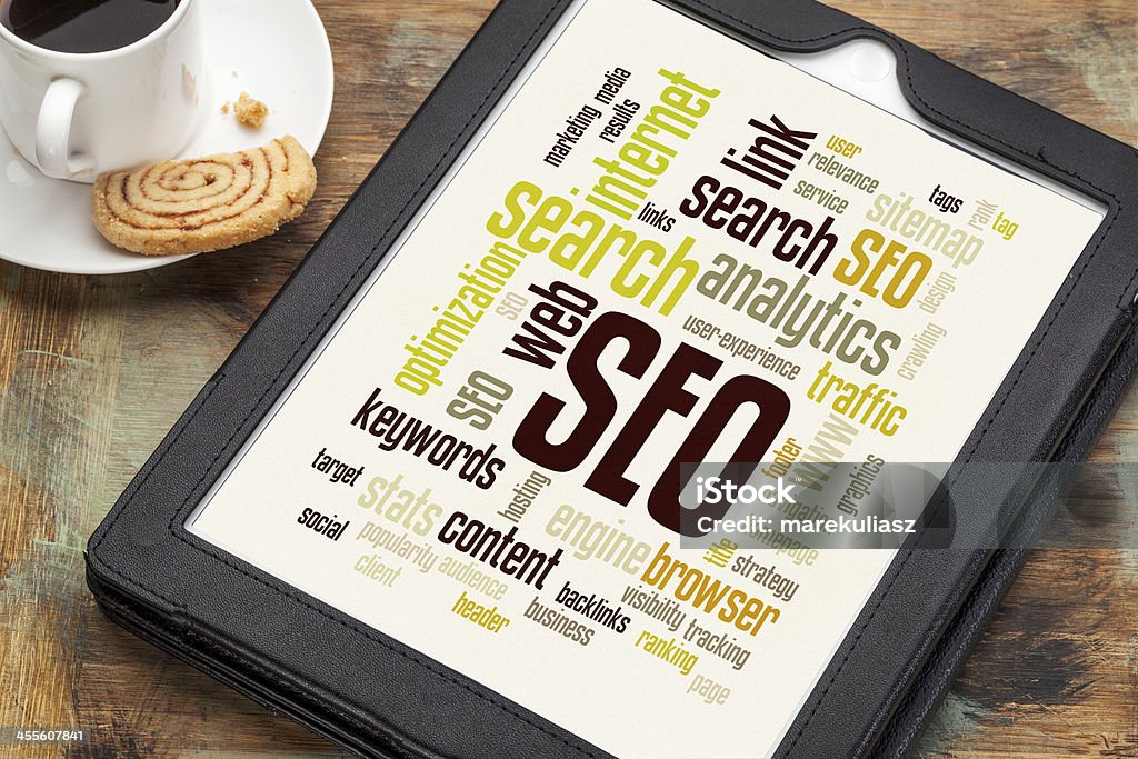 SEO word or tag cloud cloud of words or tags related to SEO (search engine optimization) on a  digital tablet with a cup of coffee Business Stock Photo