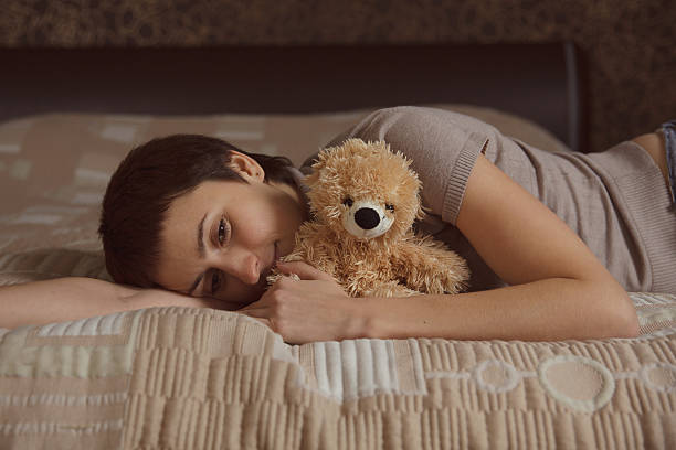 istock Young woman lying on the bed with a teddy bear 455610563