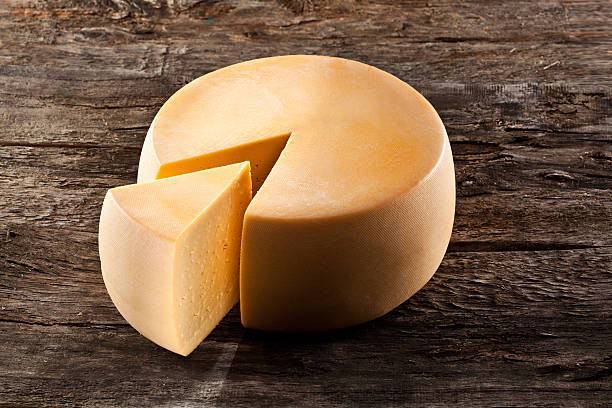 istock Cheese wheel on wooden table with wedge cut out 455613593