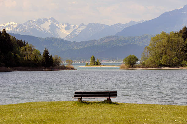 panorama landscape in Bavaria panorama landscape in Bavaria with bench at lake Forggensee nearby city Fuessen at alps mountains forggensee lake photos stock pictures, royalty-free photos & images