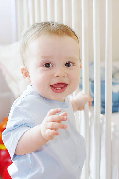 istock baby stands by white bed 455625467