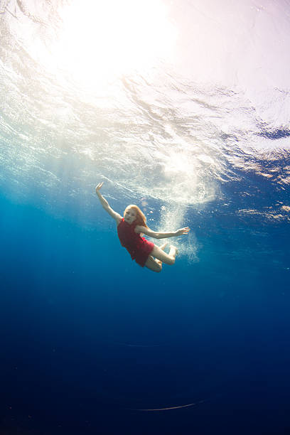 Girl swimming underwater viewed from underneath stock photo