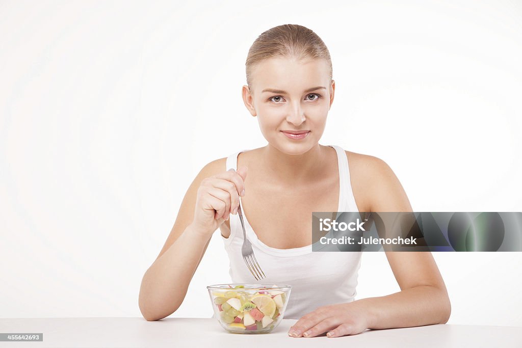 Pretty girl eating fruit salad isolated Pretty girl eating fruit salad, healthy fresh breakfast, dieting and health care concept isolated Adult Stock Photo