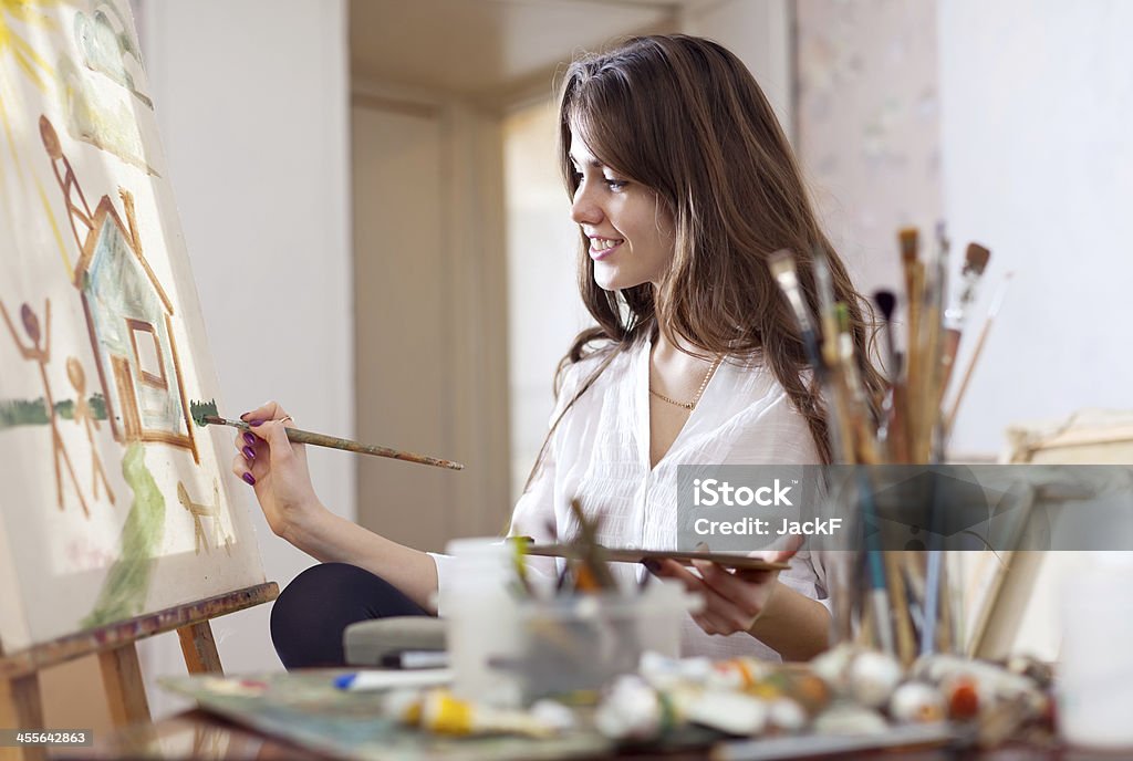 woman paints on canvas woman paints home of dreams on canvas Easel Stock Photo