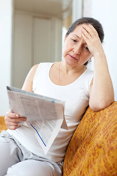 istock sadness  woman with newspaper 455642927
