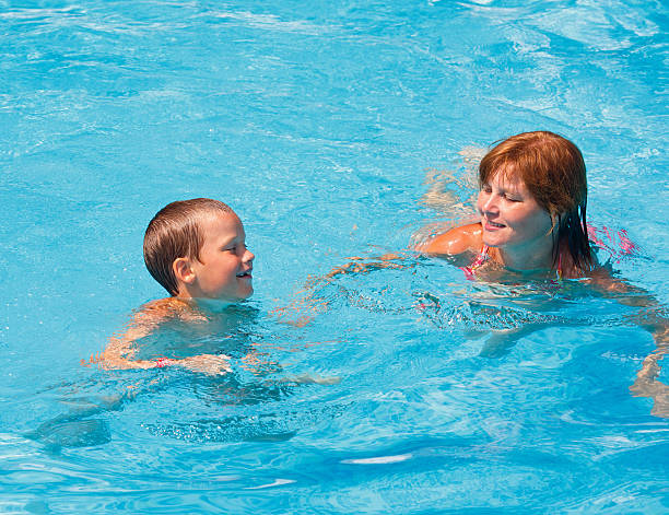 istock Mother train her son to swim in the pool. 455648237