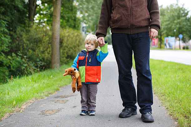 Beautiful toddler boy in colorful clothes and his father walking together