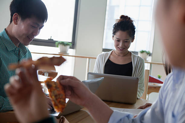 istock Coworkers eating and working in the cafeteria 455658495
