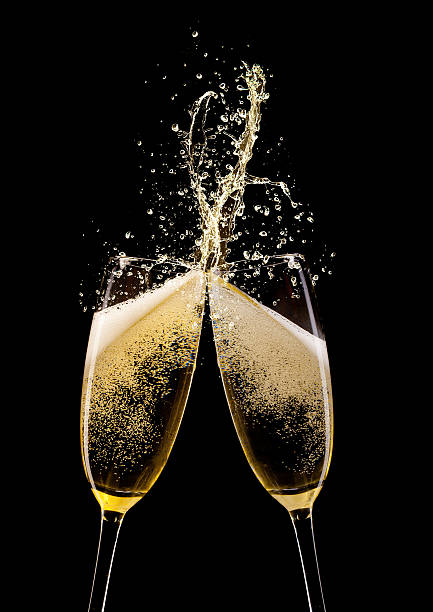 istock Two champagne flutes toasting against a black background 455658699
