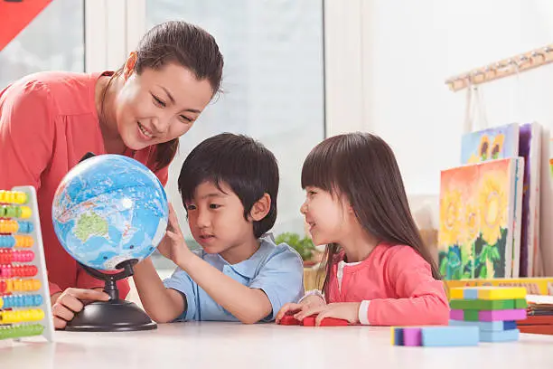 Photo of Students And Teacher Looking at Globe