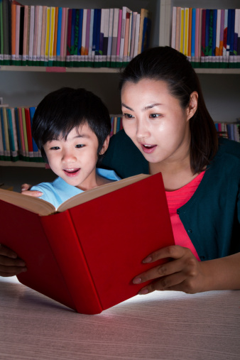 Boy and Teacher Surprised By Glowing Book