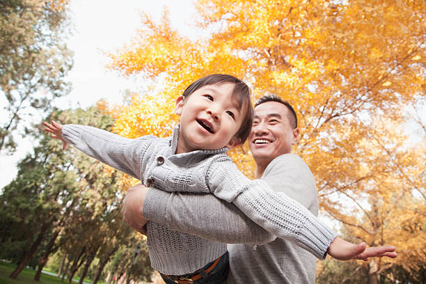 Father and son playing together at the park in autumn Father and Son Playing at Park in Autumn asia stock pictures, royalty-free photos & images