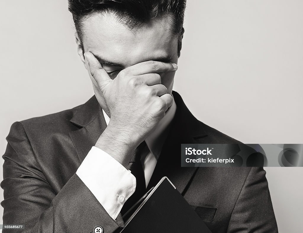 Depressed man Depressed businessman holding hand to his face. Adult Stock Photo