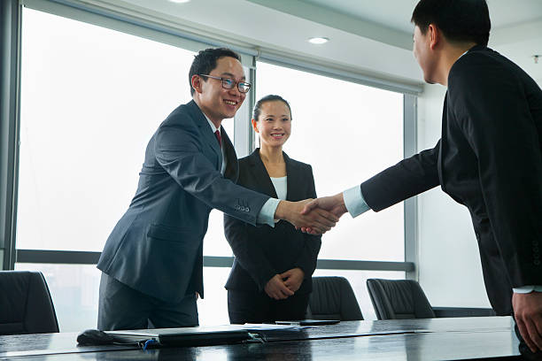 empresarios saludándose con un apretón de manos - agreement businesswoman togetherness opportunity fotografías e imágenes de stock