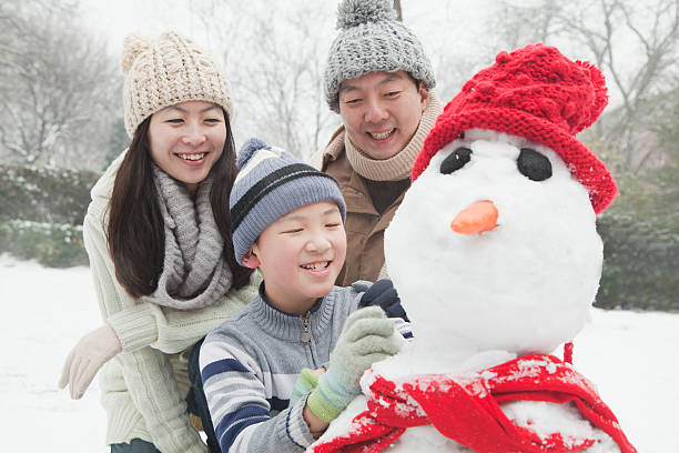 famille faisant bonhomme de neige en hiver - child winter snow asian ethnicity photos et images de collection