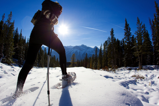 A woman enjoys a snow shoe trip on a sunny day in Alberta, Canada.