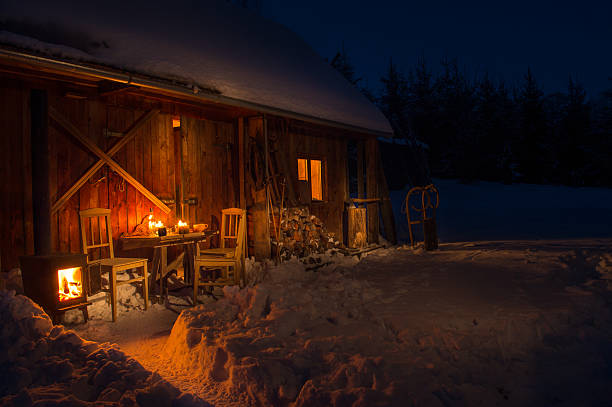 心地よい木製のコテージでダーク冬の森雪 - hut winter snow mountain ストックフォトと画像