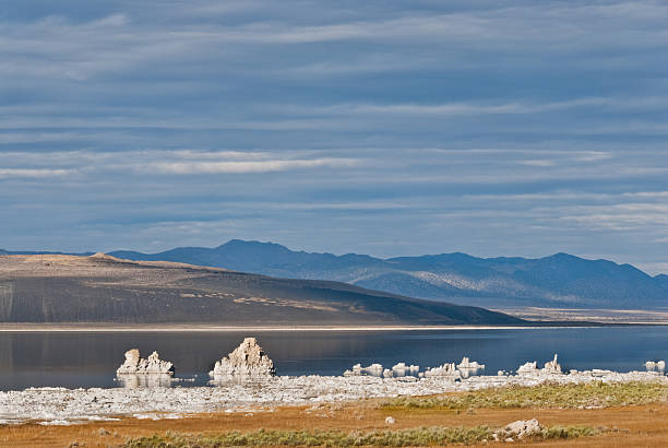 Mono Lake Tufa Formations Mono Lake in the eastern Sierra Nevada Range of California is a large, shallow saline soda lake formed at least 760,000 years ago. Because it has no outlet to the sea, high levels of salt have accumulated in the lake. These salts also contribute to the alkalinity of the lake. The lake level has dropped because water entering the lake is being being diverted into the Los Angeles aqueduct. Tufa towers, made of limestone, have appeared in the lake as the water has receded. This scene was photographed on a fall day as the sagebrush and grasses took on the glow of the setting sun. Mono Lake is in the Inyo National Forest near Lee Vining, California, USA. jeff goulden mono lake stock pictures, royalty-free photos & images