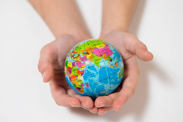 Front view of a child hand holding a damaged toy globe in front of his face