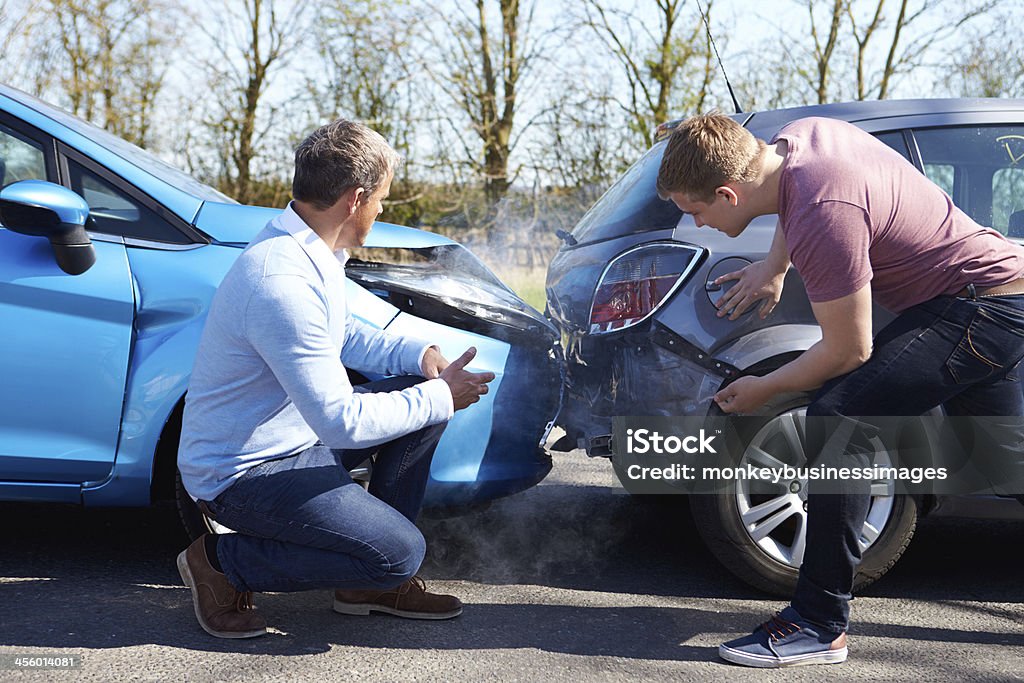 Two Drivers Arguing After Traffic Accident Two Drivers Arguing After Traffic Accident looking at damage Car Accident Stock Photo
