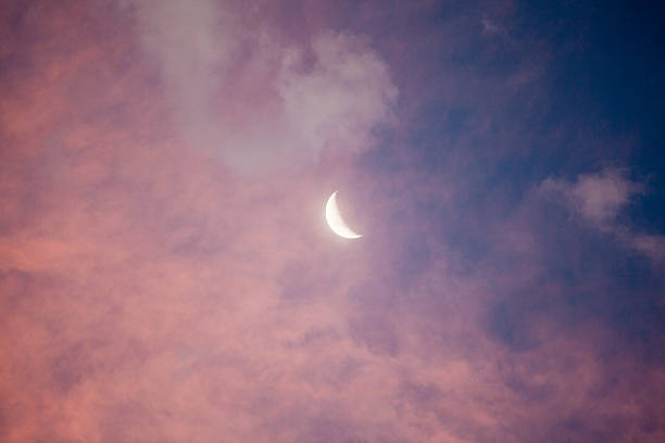 New moon with pink clouds The new crescent moon in the sky with clouds at sunset crescent photos stock pictures, royalty-free photos & images