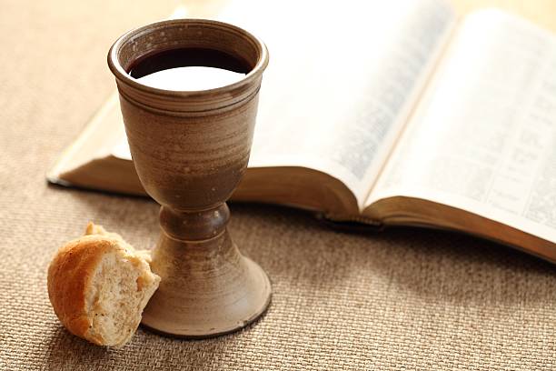 istock Holy communion wine and bread by open bible 456025963