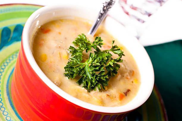 Bown of homemade corn chowder soup with parsley garnish.  Side angle view.   