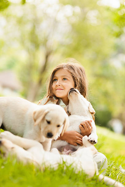 Innocent little girl playing with puppies in the garden. Vertical Shot.