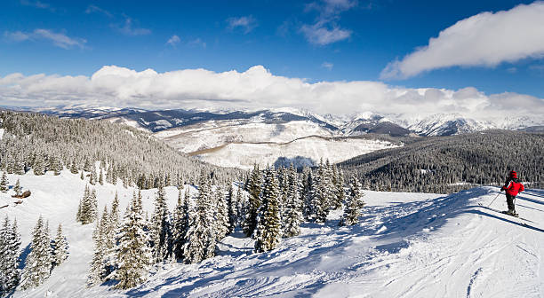 female skier standing with rocky mountains skiing slopes in background - vail eagle county colorado stockfoto's en -beelden