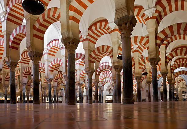 Interior of La Mezquita Cathedral (Mosque of Cordoba) in Córdoba, Spain. More than 850 columns of granite, onyx, jasper and marble support the roof. The double arches consist of a lower horseshoe arch and an upper semi-circular arch. The famous alternating red and white voussoirs of the arches were inspired by those in the Dome of the Rock. This photograph depicts columns in the part of the mosque that was built by Al-Mansur Ibn Abi Aamir in 987.