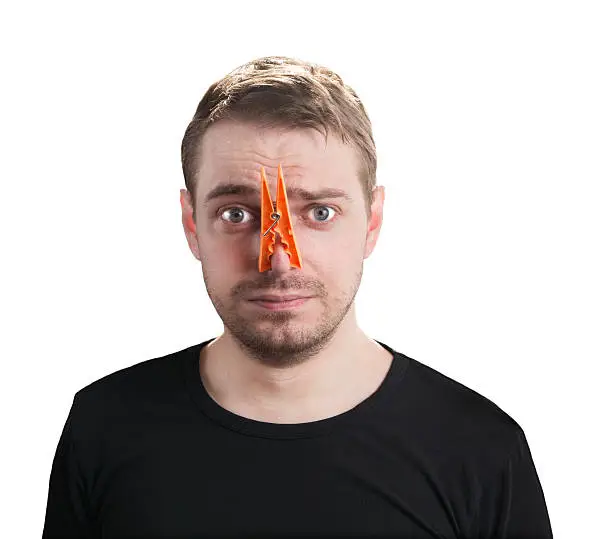 Portrait of caucasian man with orange clothespin on his nose - bad smell concept photography.