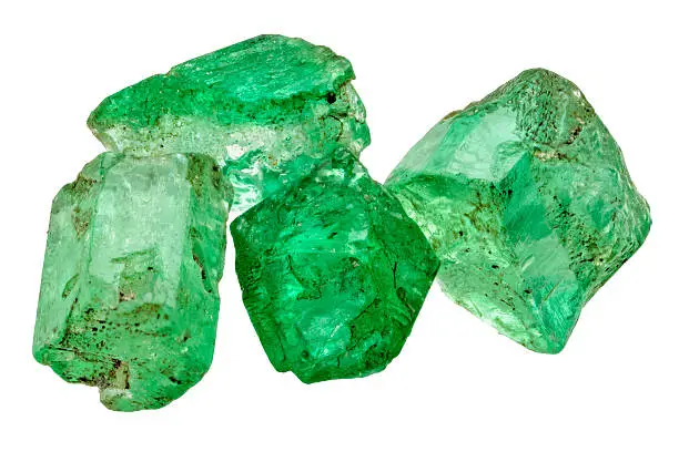 Four rich green emerald crystals on white