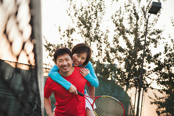 chłopak trzymając jego dziewczyna obok siatka do tenisa - tennis men vitality joy zdjęcia i obrazy z banku zdjęć