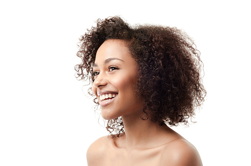 Image of a young ethnic woman with a toothy smile looking away from the camera