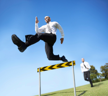 A businessman jumping over a hurdle