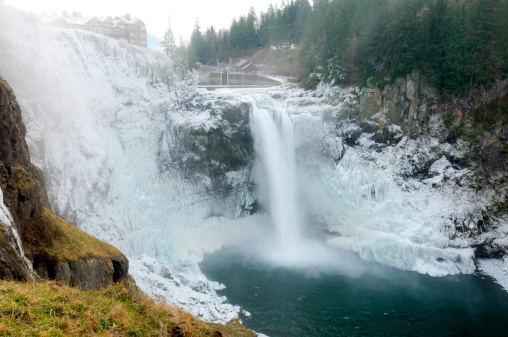 High Dynamic Range image of Snoqualmie Falls with mist rising and forming ice on the surrounding cliffs.
