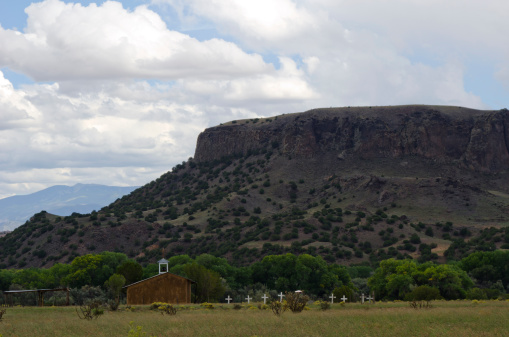 An old cemetery marked with large white crosses, sits next to La Capilla de Sagrada Familia, the Chapel of the Holy Family, at the base of Black Mesa in the San Ildefonso Pueblo in northern New Mexico.