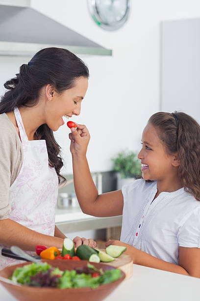 istock Daughter giving a cherry tomato to her mother 456072357