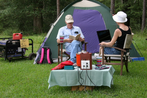 Mature couple at a campsite.  They use the new fuel cell to generate electricity in lieu of the old style gasoline generator.  Generator is now 
