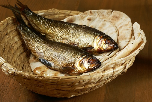 Loaves of bread and two fishes in a basket.