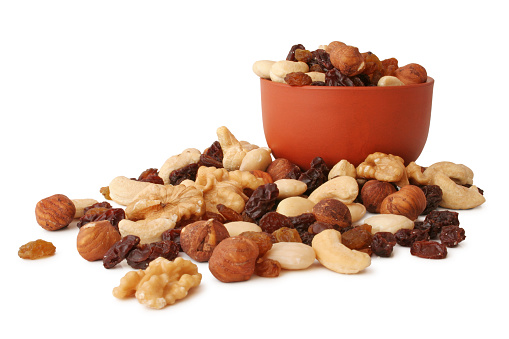 Nuts and raisins with terracotta bowl isolated on white background.               