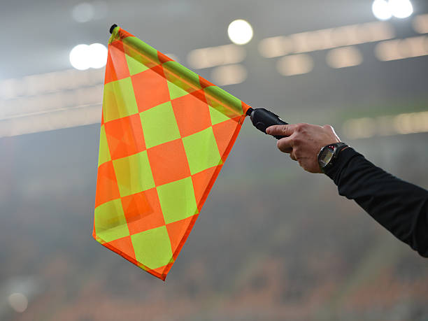 A orange an yellow checkered flag Raised referee flag. offside stock pictures, royalty-free photos & images