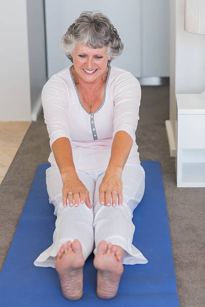 istock Mature woman stretching her legs on blue mat 456106201