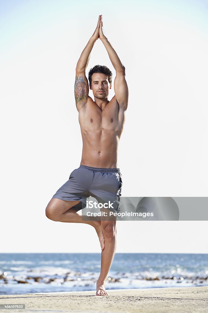 At one with nature and his body Full length shot of a young man exercising at the beach Yoga Stock Photo