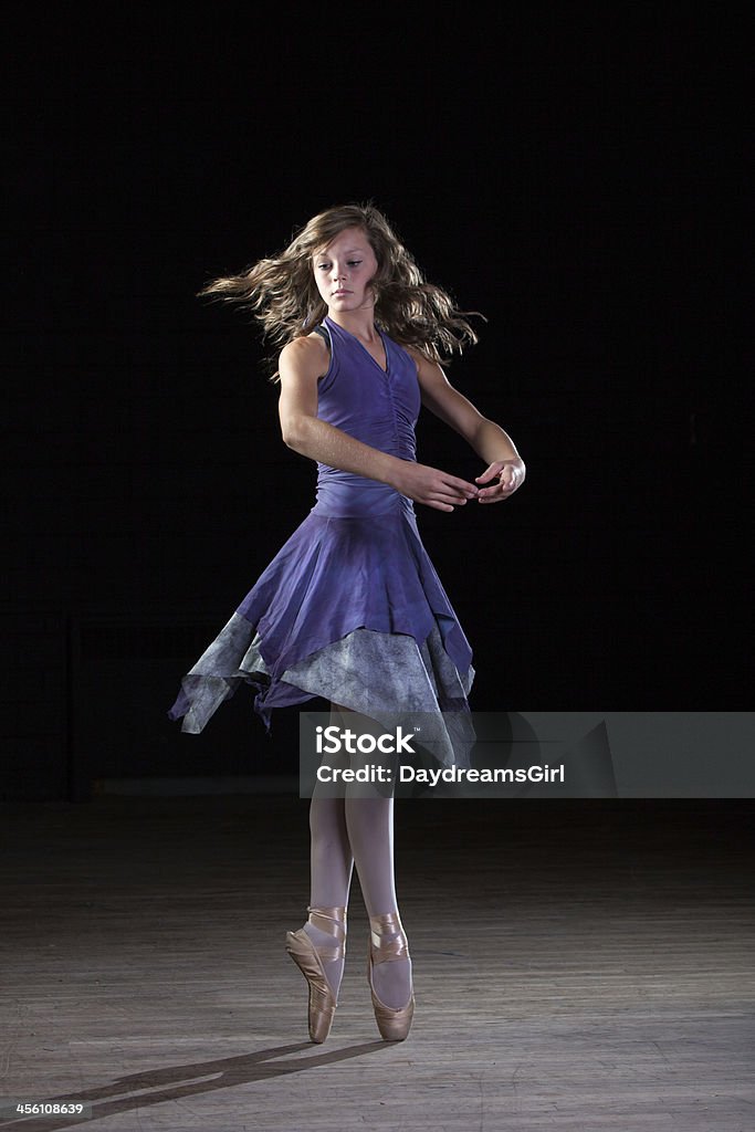 Beautiful Ballerina Twirling on Toes Ballerina on dark stage dancing on tip toes. Adult Stock Photo