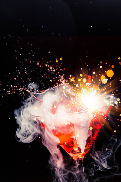 Red cocktail in a martini glass splashing out