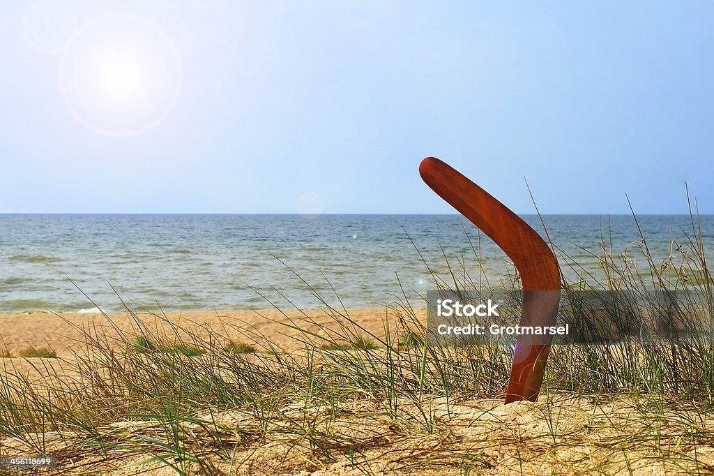 Landscape with boomerang on overgrown sandy beach. Landscape with boomerang on overgrown sandy beach against blue sea and sky. Boomerang Stock Photo